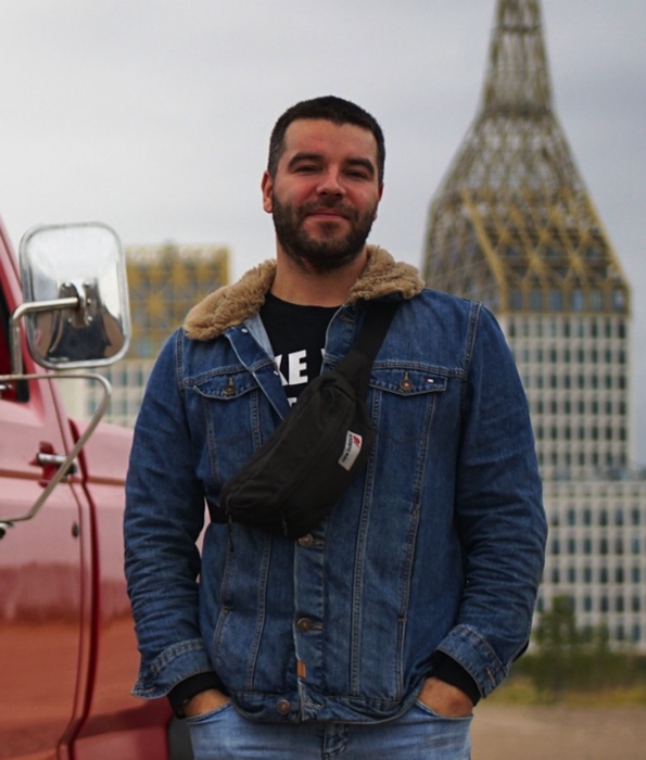 Алексей Крылов, основатель «Тяжёлой Техники», в джинсовой куртке у красного автомобиля